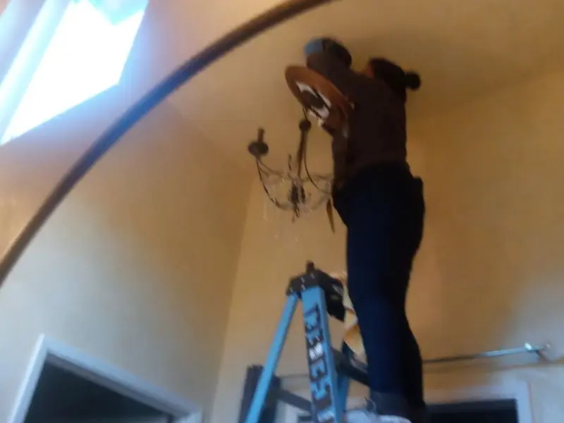 Electrician installing a chandelier in a Fort Hood residence